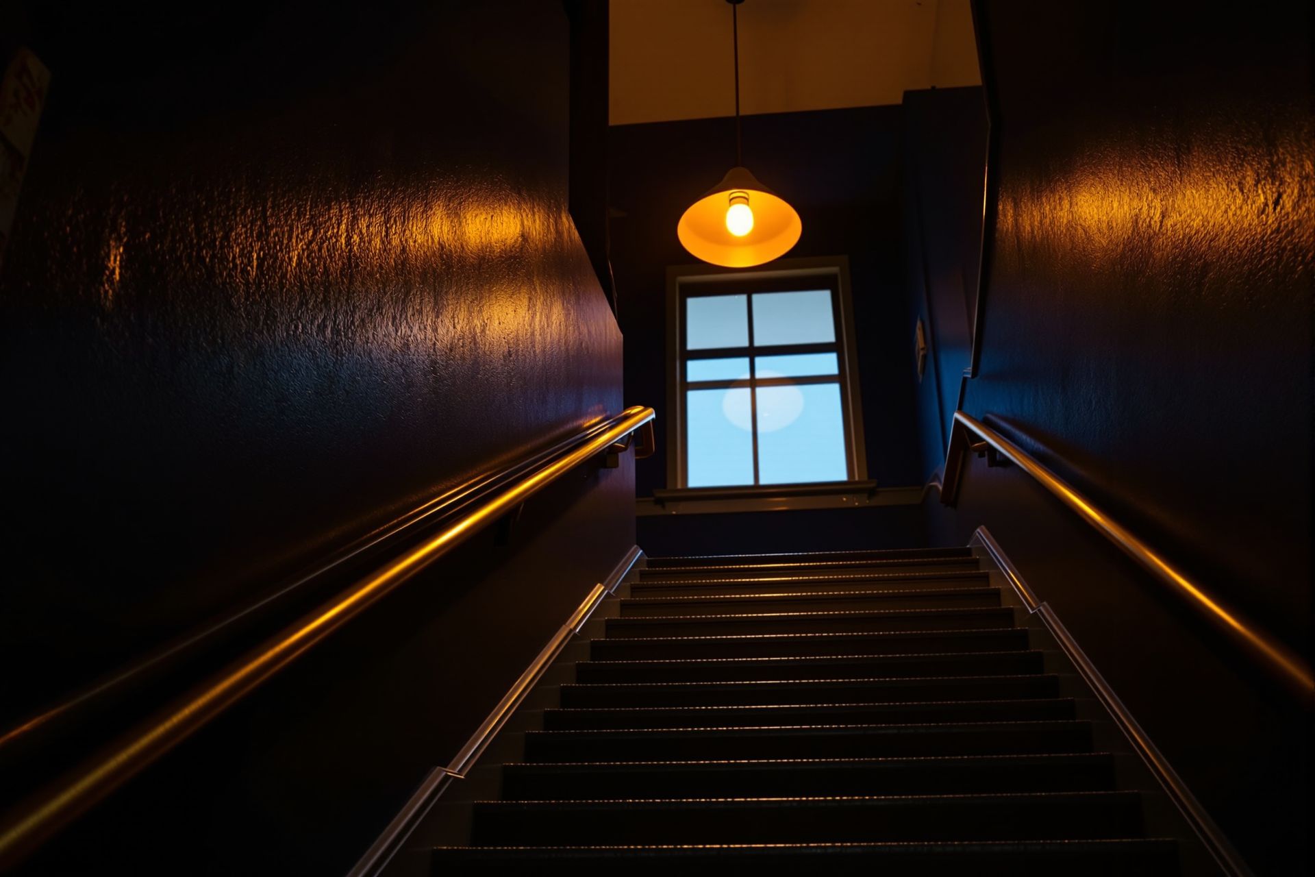 A staircase with a polished brass handrail in an old office building at dusk
