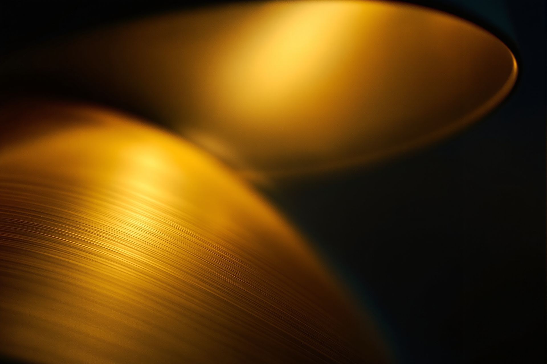 Brushed brass catching warm lamp light against deep navy shadow, very close